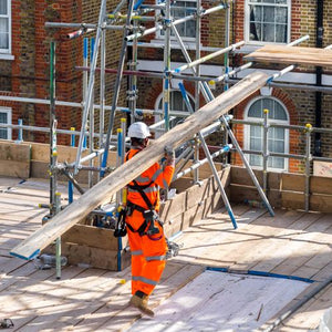 Worker carrying scaffold board